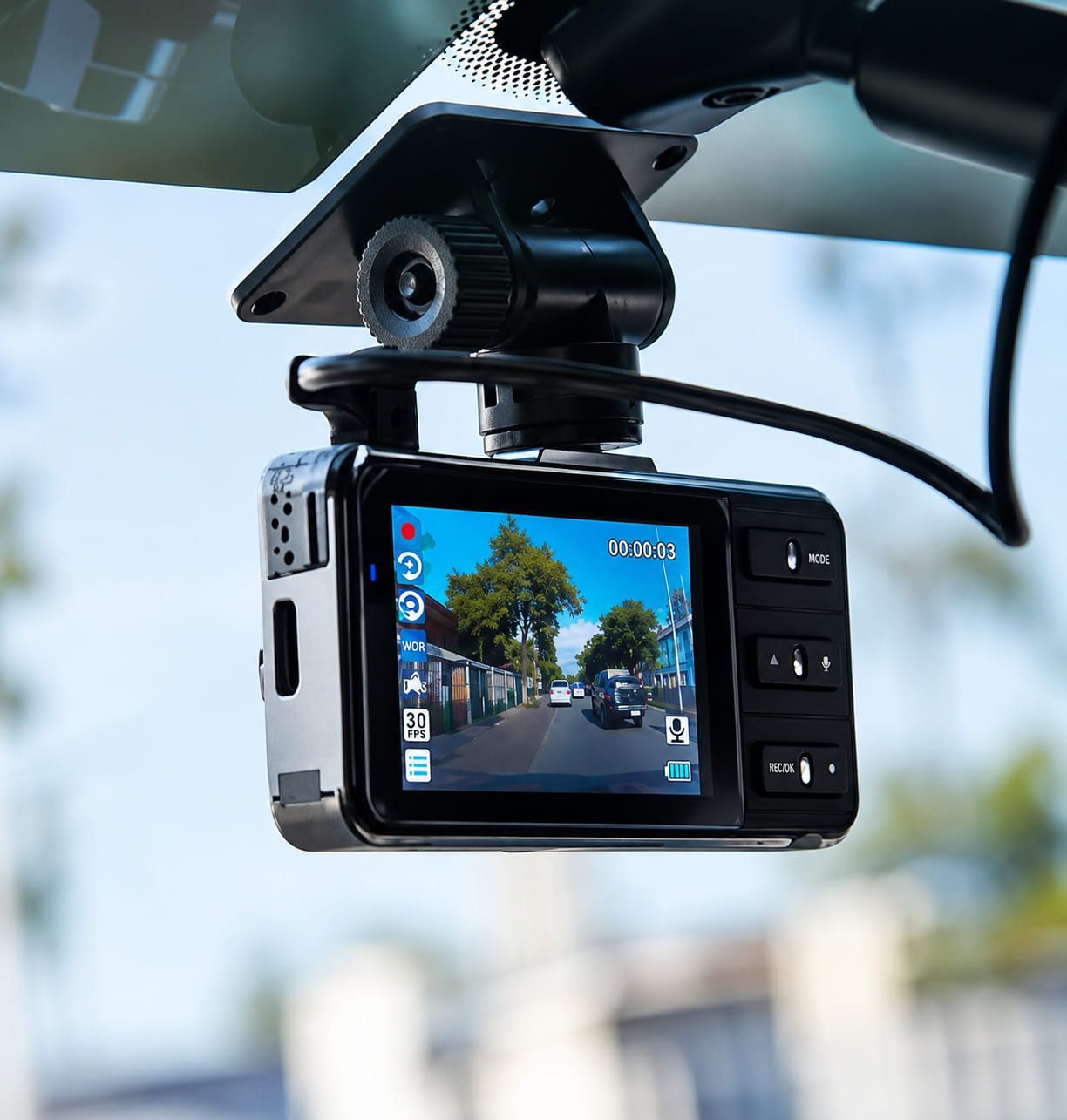 A road-facing PrimeTrack dash camera mounted on a windscreen, its screen showing the live forward view
